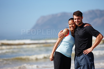 Buy stock photo Shot of an affectionate young couple posing in sports gear on a beach