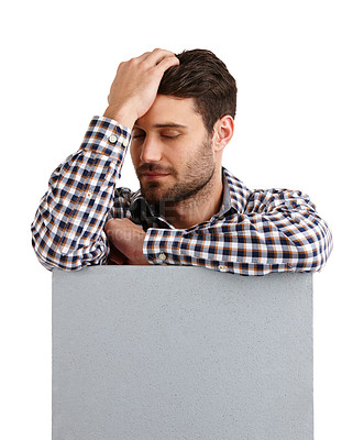 Buy stock photo Studio shot of a handsome young man leaning on a blank placard with his eyes closed isolated on white