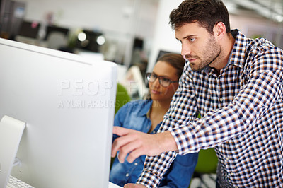 Buy stock photo Cropped shot of a handsome young man assisting a female colleague with something on her computer
