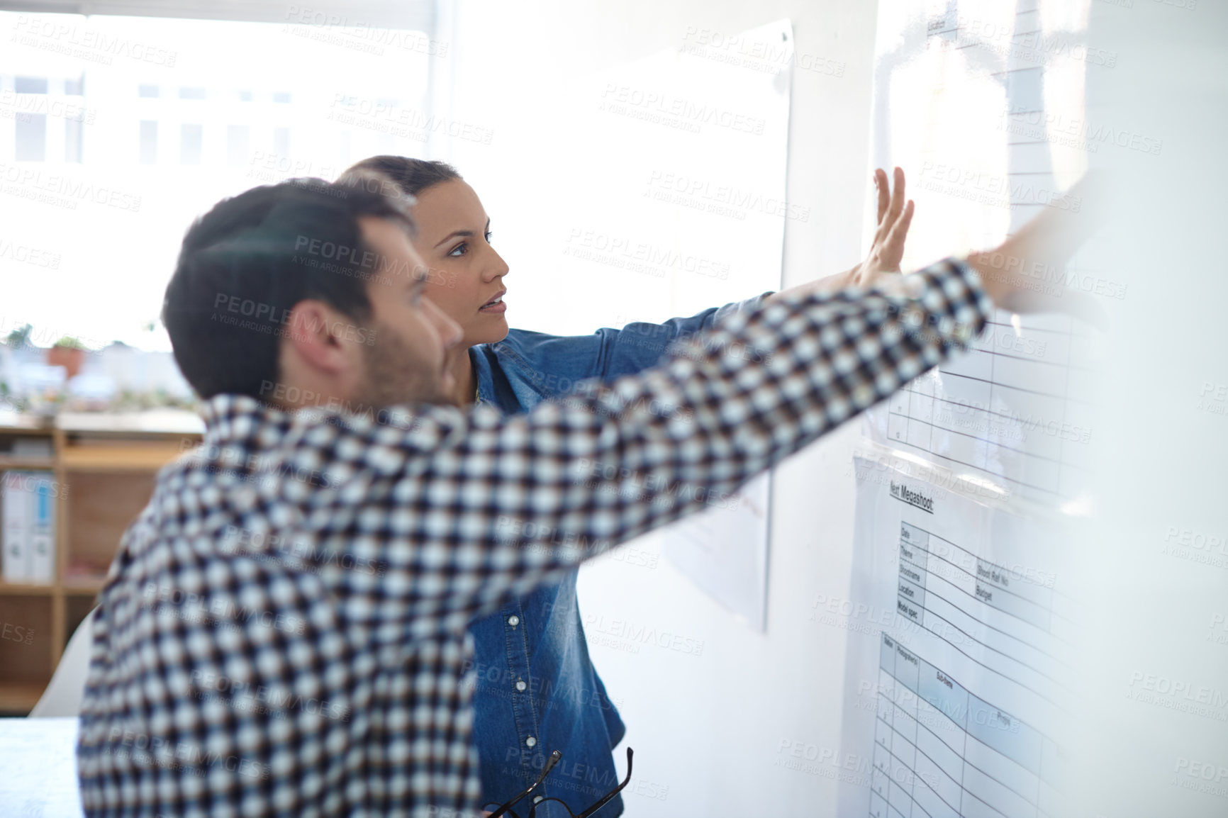 Buy stock photo Cropped shot of two colleagues discussing work at a whiteboard