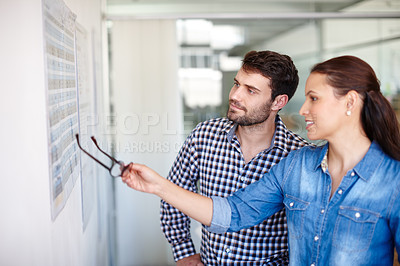 Buy stock photo Cropped shot of two colleagues discussing work at a whiteboard