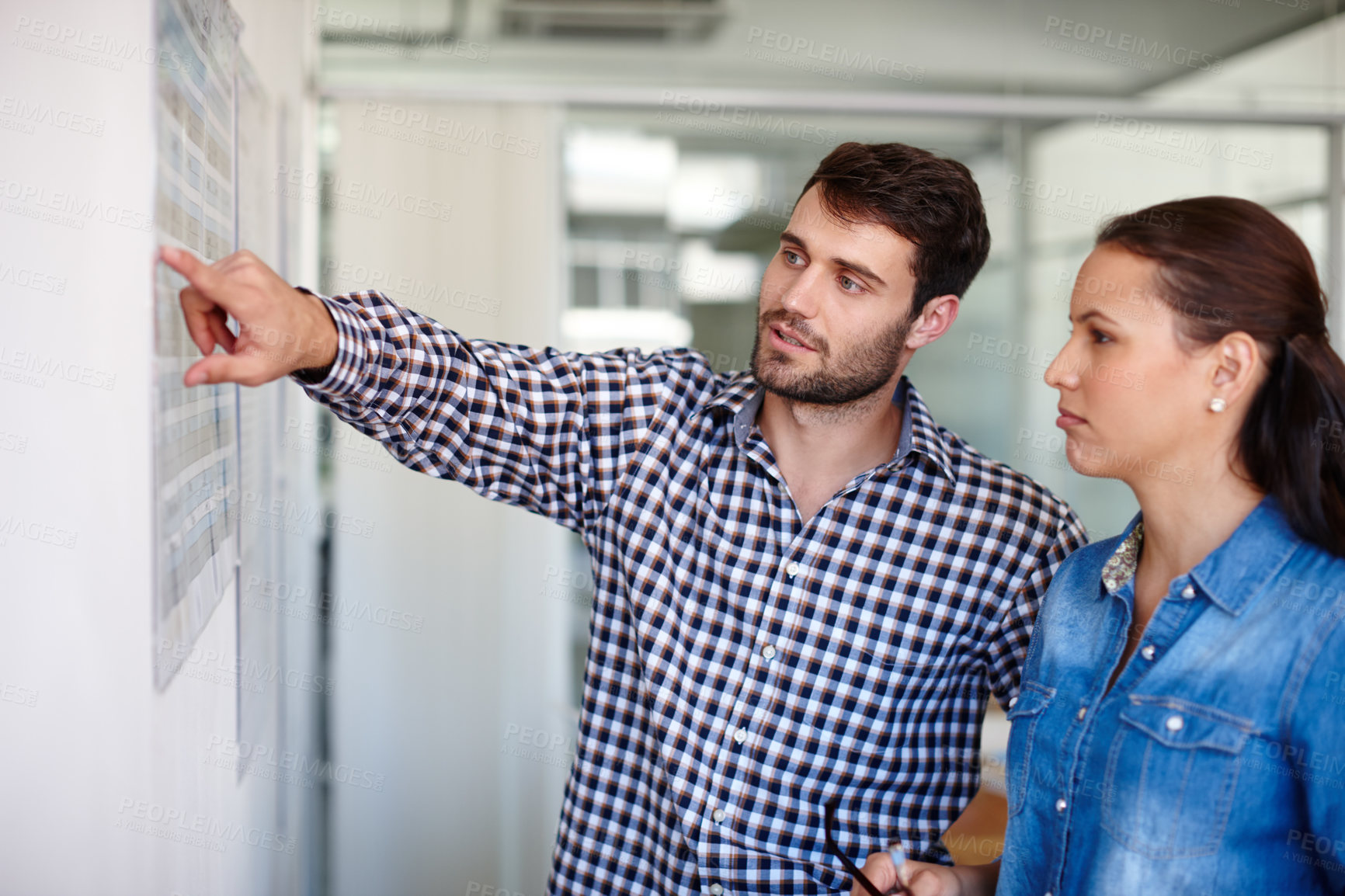 Buy stock photo Cropped shot of two colleagues discussing work at a whiteboard