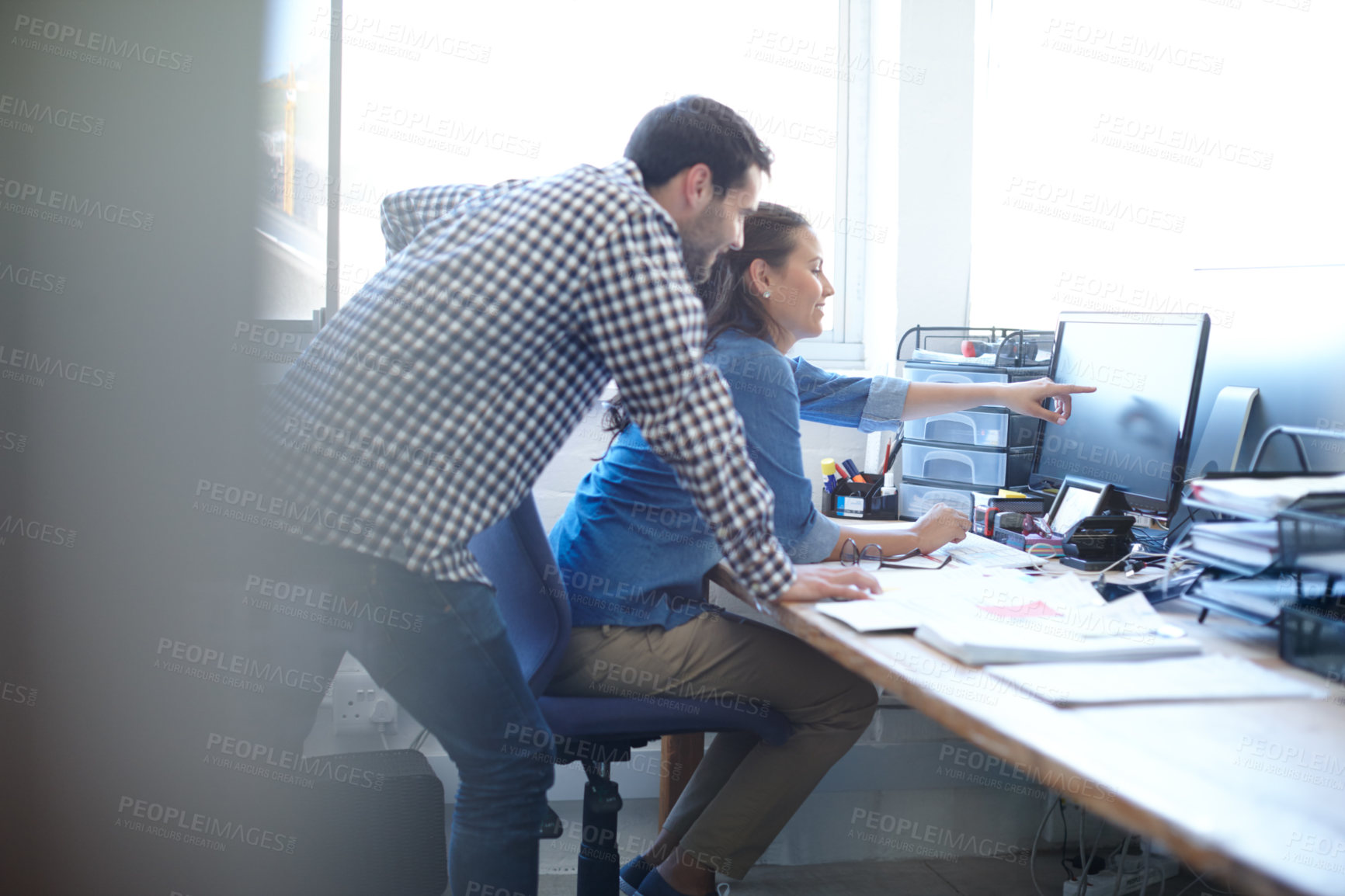 Buy stock photo Cropped shot of a handsome young man assisting a female colleague with something on her computer