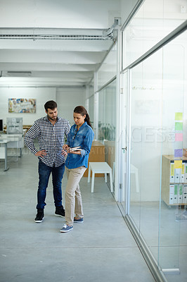 Buy stock photo Full length shot of two colleagues discussing work while standing in the office