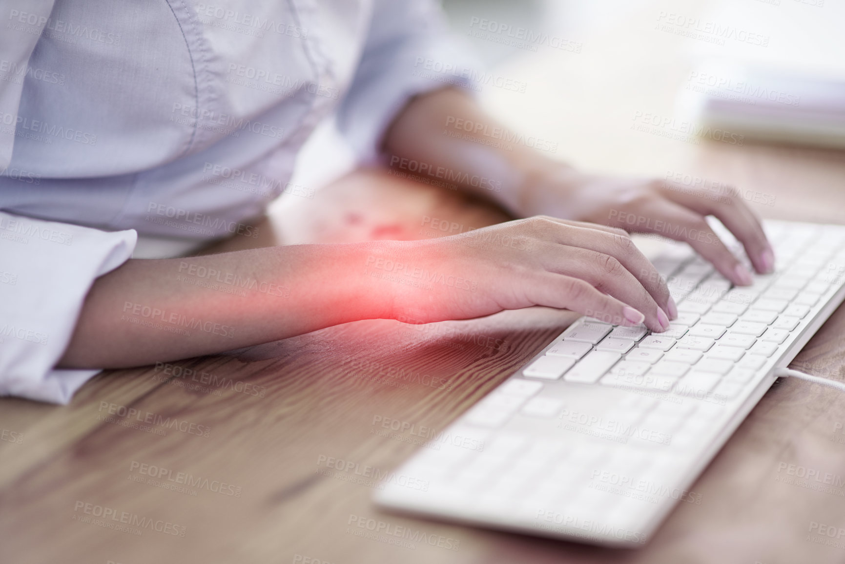 Buy stock photo Cropped shot of a businesswoman typing at her desk with her sore wrists highlighted in red