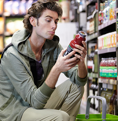 Buy stock photo Man, label and product in supermarket for decision, consider or grocery shopping nutrition choice. Male person, thinking and bottle shelf store search or reading price, diet value or buy organic