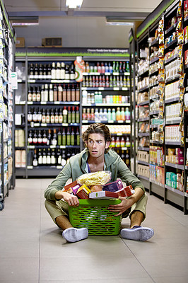 Buy stock photo Man, grocery shopping and shop, stress about inflation and expensive food, overwhelmed in supermarket. Groceries in basket, retail and customer shocked by price, choice and purchase with fear