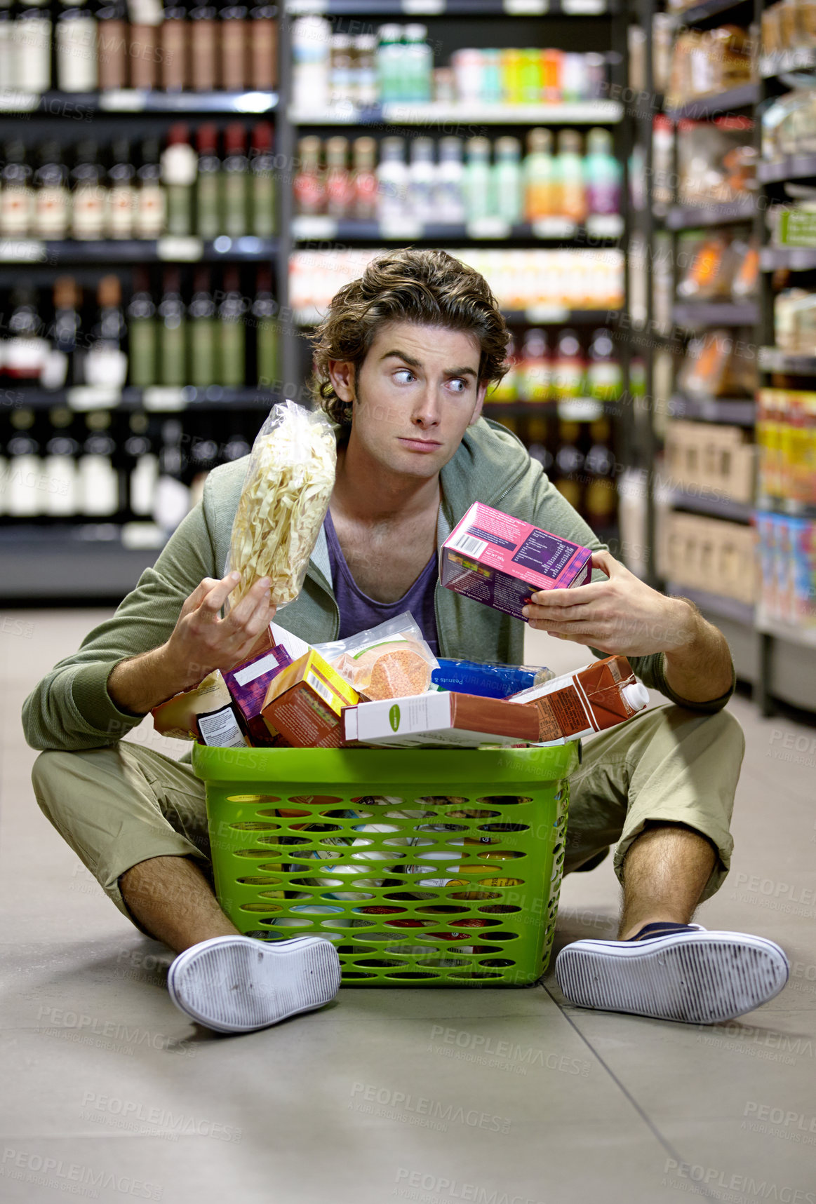 Buy stock photo A young man sitting on the floor anxiously overwhelmed by grocery shopping