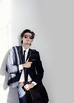 Buy stock photo Fashion, elegant and handsome man by a wall with stylish, cool and trendy outfit and briefcase. Sunglasses, bag and young male model from Canada with formal and classy style by white background.