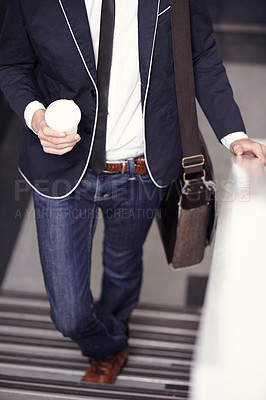 Buy stock photo Cropped image of a trendy young man walking up the stairs with coffee