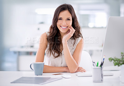 Buy stock photo Shot of an attractive businesswoman sitting at her desk in an office