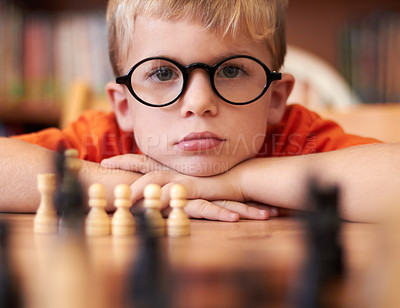 Buy stock photo Young boy wearing spectacles and playing chess