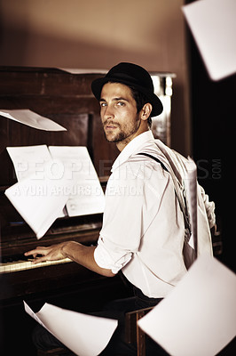 Buy stock photo Portrait of a handsome young musician sitting at a piano with sheet music falling all around him