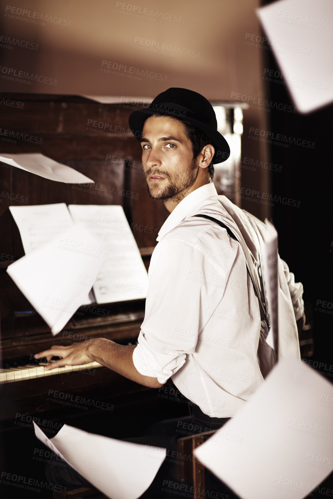 Buy stock photo Portrait of a handsome young musician sitting at a piano with sheet music falling all around him