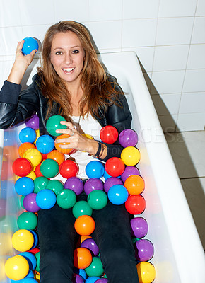 Buy stock photo Portrait, balls and happy woman in bathtub for fashion, style and trendy hipster at home. Smile of person in tub with color, sphere or plastic in bathroom, relax and edgy or cool clothes in Canada