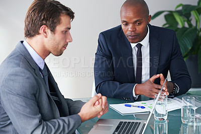 Buy stock photo Shot of two businessmen discussing work while sitting with a laptop