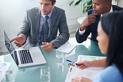 Buy stock photo Shot of a businessman showing his colleagues something on a laptop during a meeting