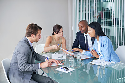 Buy stock photo Shot of a group of businesspeople going over documents during a meeting