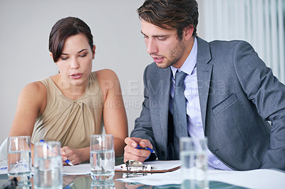 Buy stock photo Shot of two business colleagues discussing paperwork in a meeting
