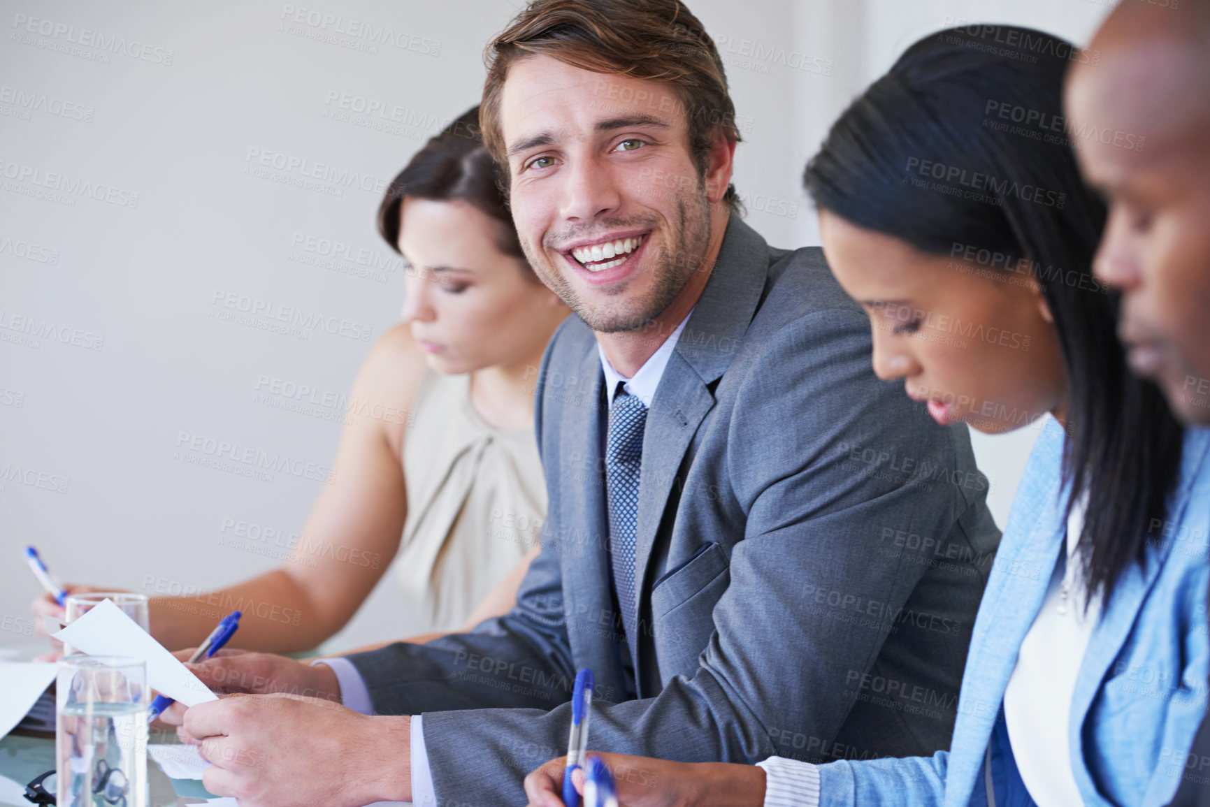 Buy stock photo Portrait of a young businessman sitting in a meeting with his colleagues