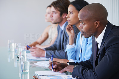 Buy stock photo Shot of businesspeople taking notes while listening to a presentation at a conference