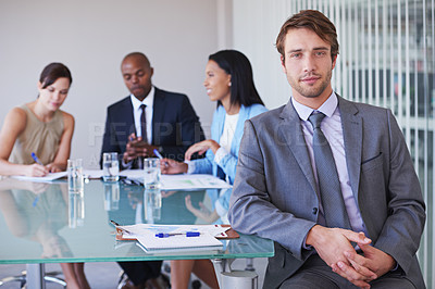 Buy stock photo Portrait of a young businessman with his colleagues having a meeting in the background