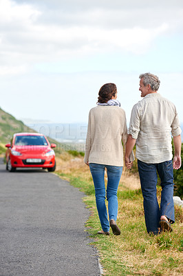 Buy stock photo Old couple, walking and holding hands in nature on holiday, vacation or retirement with support. Back, man and woman with love, car and happiness in marriage together on a road trip or journey