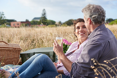 Buy stock photo Mature, couple relax and picnic in park on date with love, care or support in marriage. Outdoor, man and woman on grass in nature with drink, flowers or celebration in summer, holiday or vacation