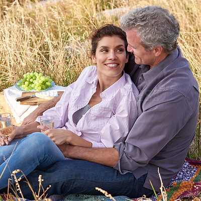 Buy stock photo Mature couple, date and picnic in park to relax with love, care or support in marriage. Outdoor, man and embrace woman on grass in nature with food, drinks or celebration together on vacation