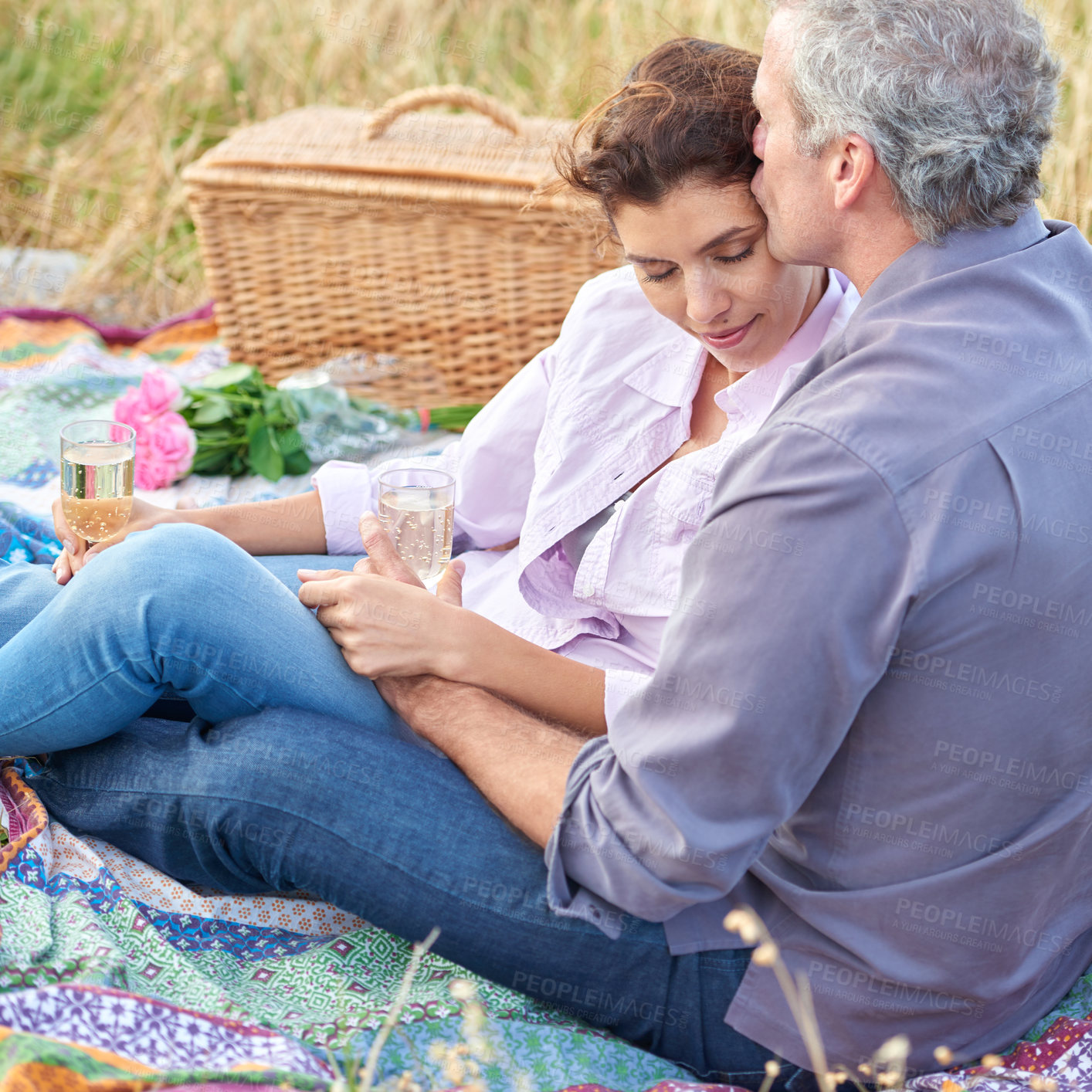 Buy stock photo Kiss, senior couple and picnic in park, grass and basket in nature for a date or celebration with love and care. Mature, woman and man in field in summer, holiday or vacation with wine or drinks
