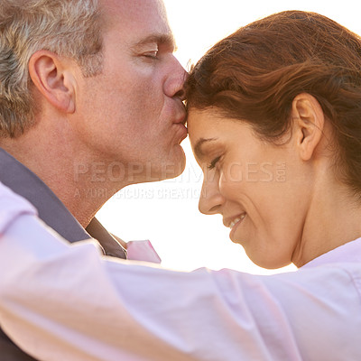 Buy stock photo Couple, forehead kiss and hug with love, respect or happiness on holiday in romance. Mature, man and woman embrace together outdoor at sunset on vacation or show affection or gratitude in marriage