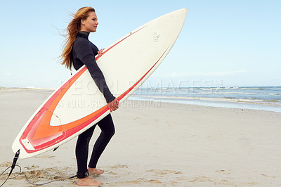 Buy stock photo Shot of a female surfer standing on the beach with her surfboard