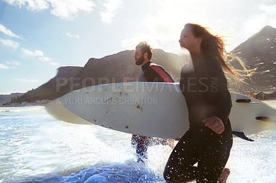 Buy stock photo Shot of an athletic young couple surfing at their favourite beach