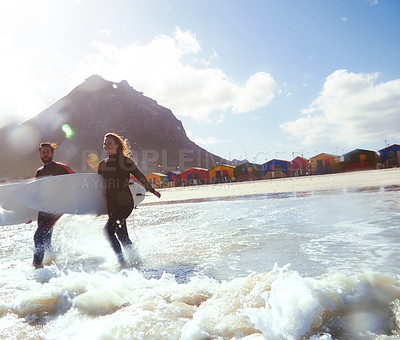 Buy stock photo Shot of an athletic young couple surfing at their favourite beach