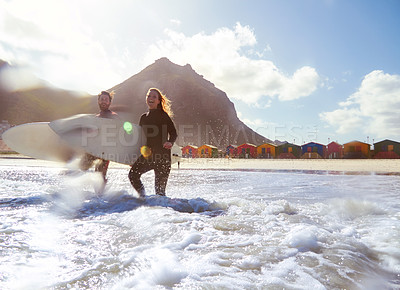 Buy stock photo Shot of an athletic young couple surfing at their favourite beach