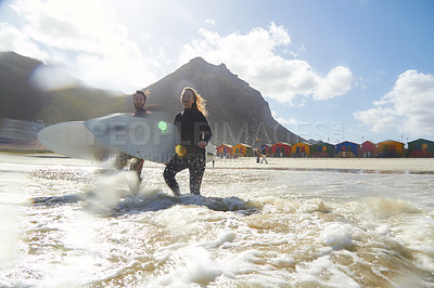 Buy stock photo Shot of an athletic young couple surfing at their favourite beach