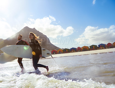 Buy stock photo Shot of an athletic young couple surfing at their favourite beach