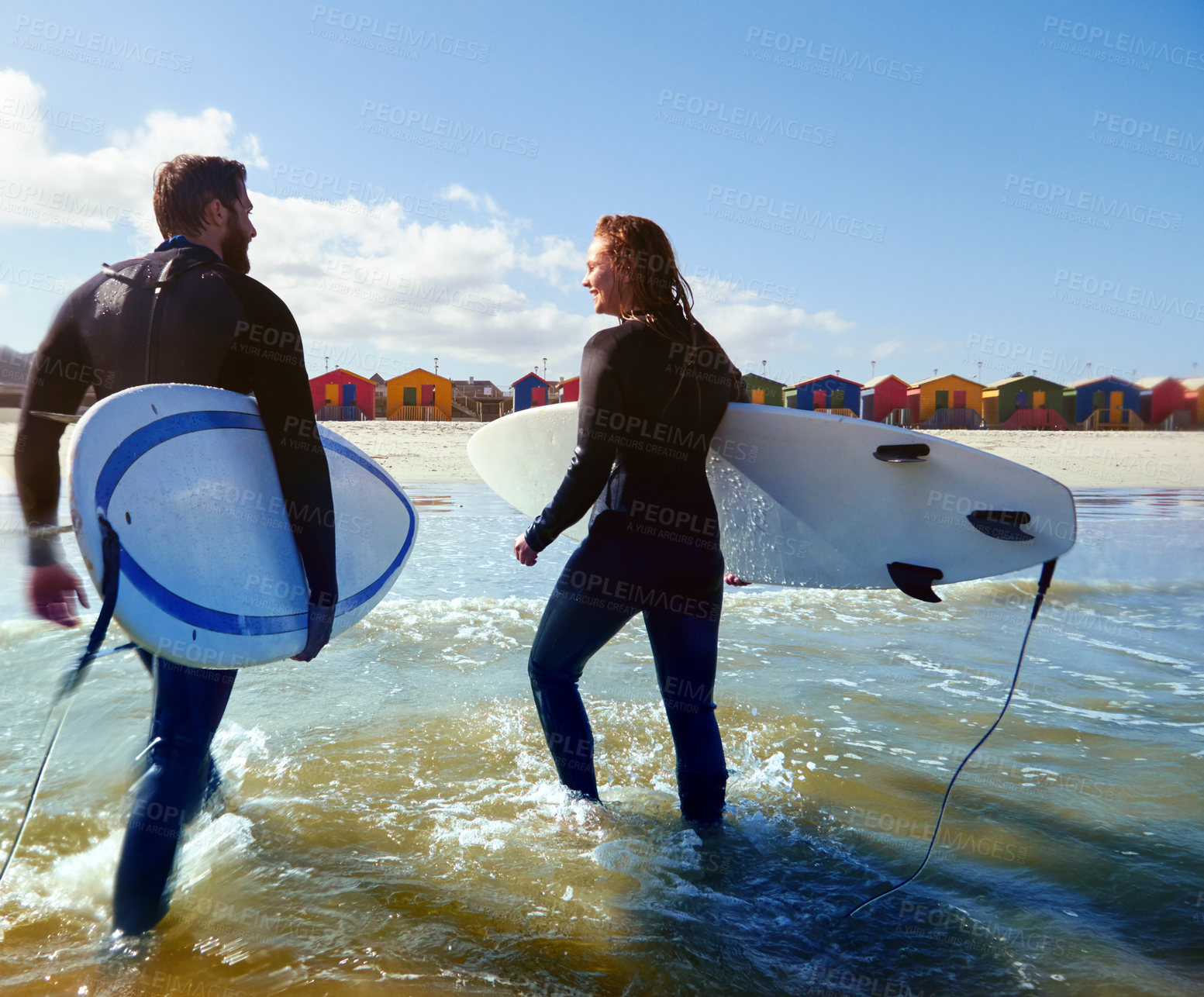 Buy stock photo Rearview shot of an athletic young couple surfing at their favourite beach