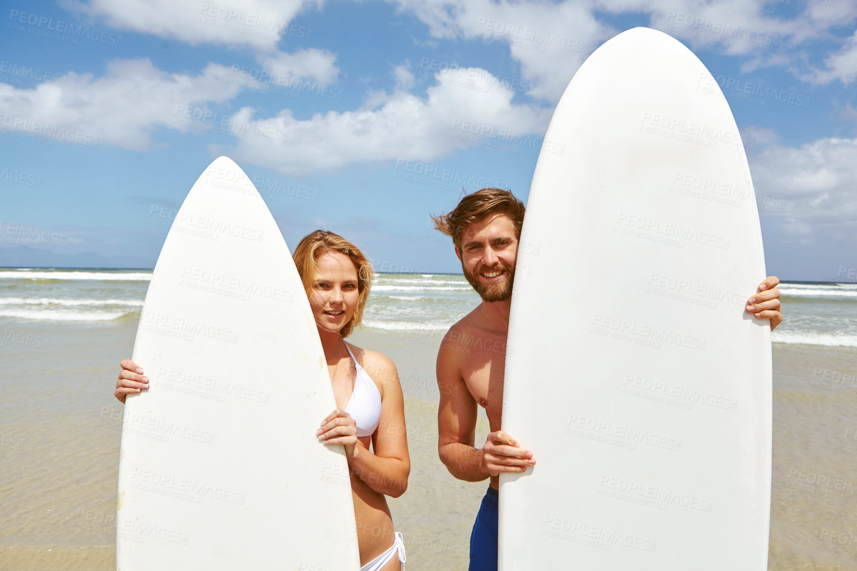 Buy stock photo Shot of a young couple standing alongside their surfboards on the beach