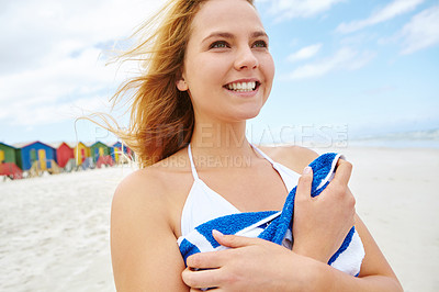 Buy stock photo Cropped shot of a beautiful young woman standing on the beach holding her beach towel