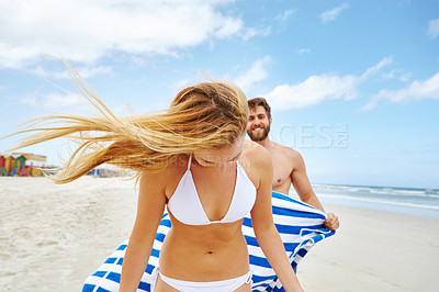 Buy stock photo Shot of a happy young couple being playful at the beach