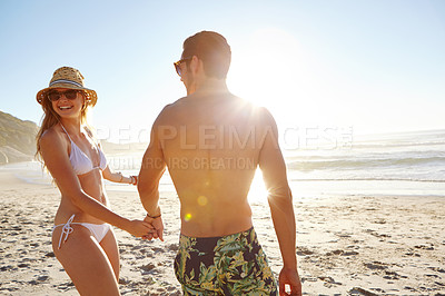 Buy stock photo Shot of a young couple in swimwear enjoying the late afternoon sun at the beach