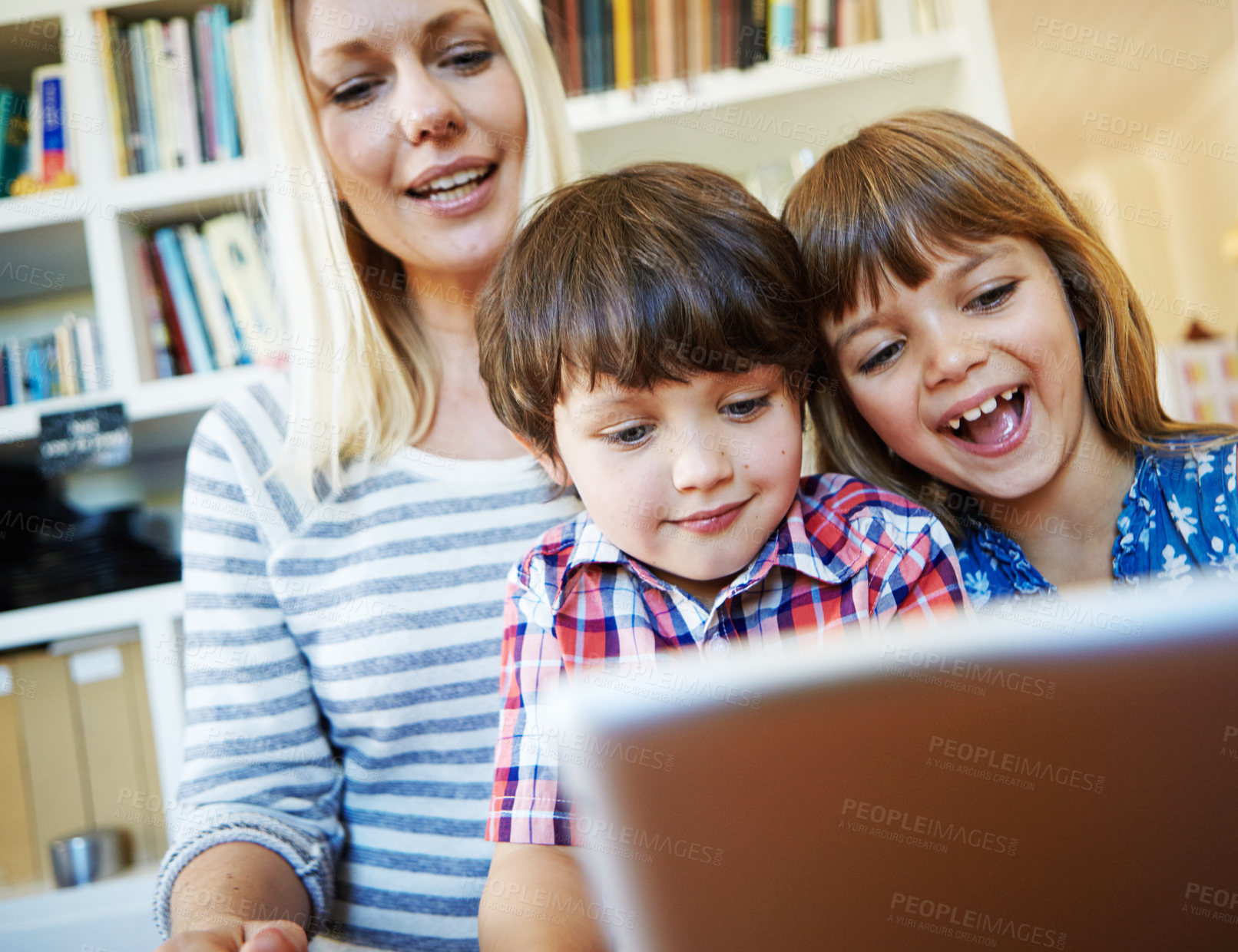 Buy stock photo Shot of a young brother and sister using a digital tablet together while their mother looks on