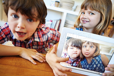 Buy stock photo Shot of a young brother and sister showing you their selfie on a digital tablet