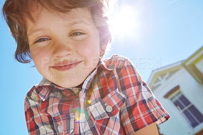 Buy stock photo Low angle portrait of a young boy outdoors with his home in the background