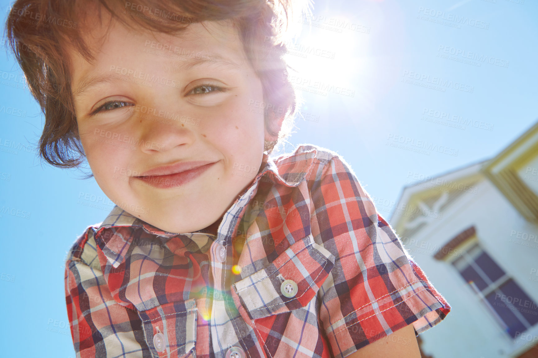 Buy stock photo Low angle portrait of a young boy outdoors with his home in the background