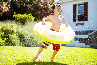 Buy stock photo Shot of a little boy playing outside in the water from the sprinkler