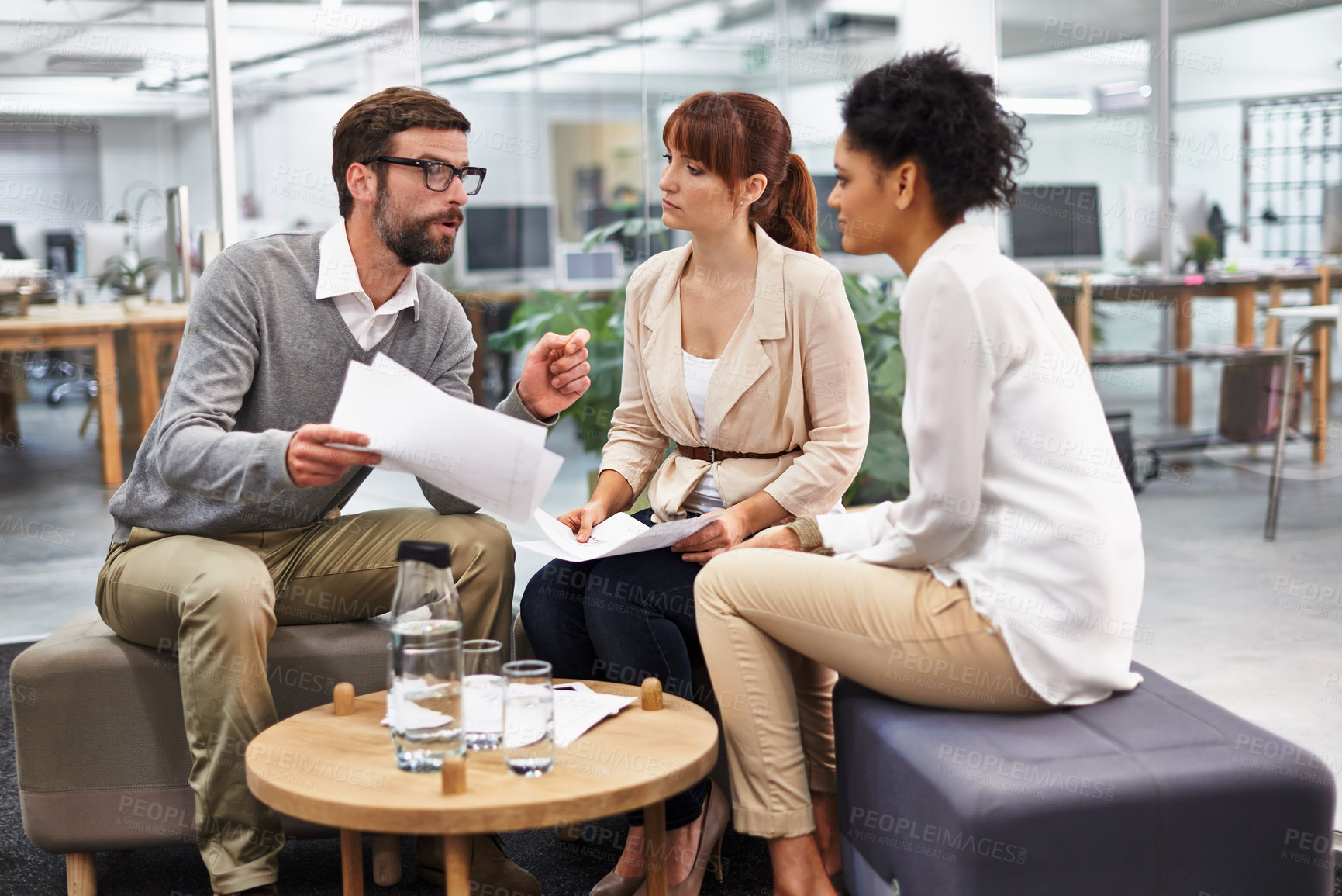 Buy stock photo Shot of a diverse group of young professionals discussing paperwork