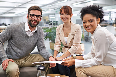 Buy stock photo Shot of a group of young professionals discussing paperwork