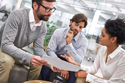 Buy stock photo Shot of a group of young professionals discussing paperwork